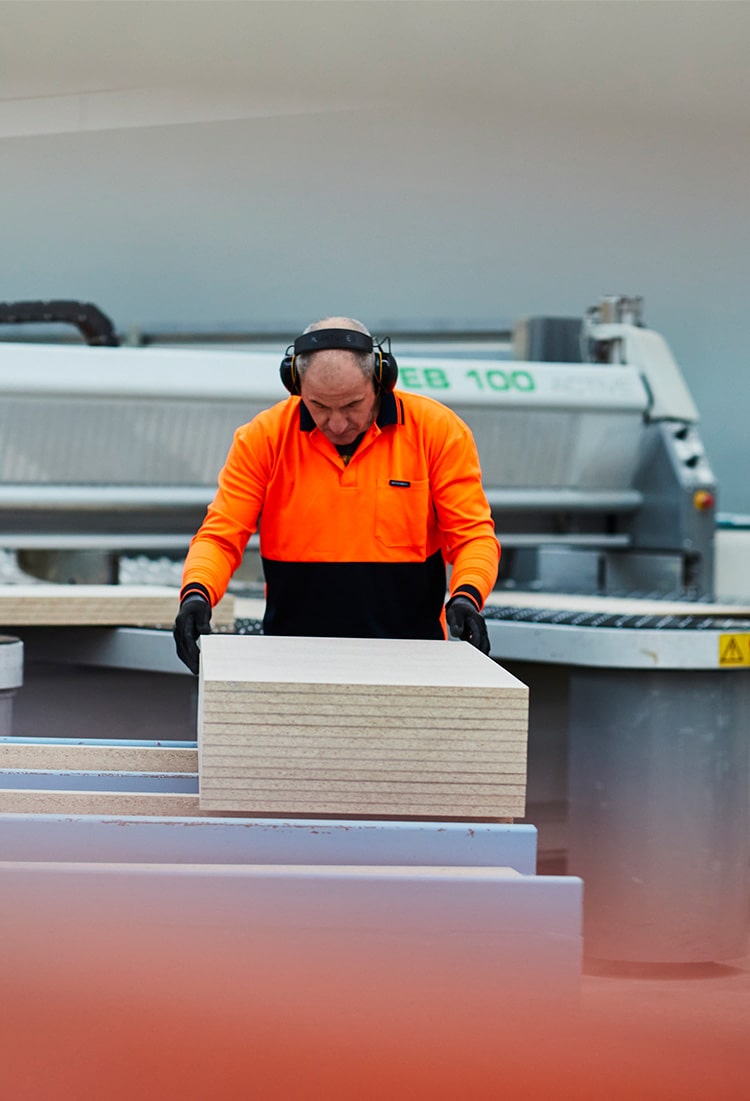 Medium shot of a beam saw operator organising cut to size particle board panels in a Melbourne warehouse